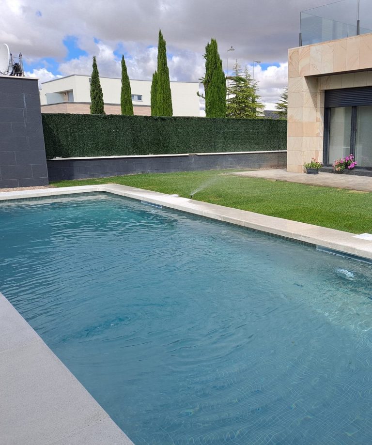 Construccion dePiscina  aqbierta con agua clara, césped verde y árboles en un ambiente moderno y despejado.